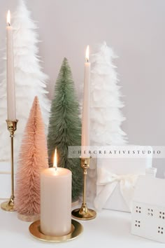 three lit candles sitting on top of a table next to small christmas trees and decorations