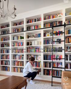 a person kneeling down in front of a book shelf filled with books