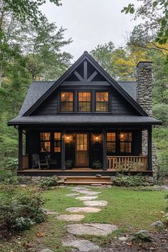 a small black cabin in the woods with stone steps leading up to it's front door