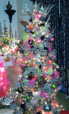 a brightly colored christmas tree in a living room with lights and ornaments on the top