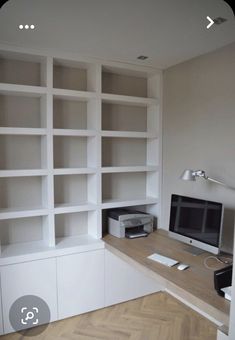 a desk with a computer on top of it in front of some bookshelves