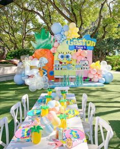 a table set up for a spongebob birthday party with balloons and pineapples