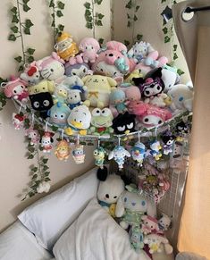 a bunch of stuffed animals are hanging from the ceiling above a bed with white sheets