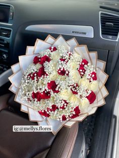 a bouquet of white and red roses in the front seat of a car, with baby's breath