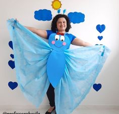 a woman wearing a blue dress and holding up a large piece of paper with hearts on it