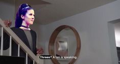 a woman with blue hair is standing on the stairs in front of a round mirror