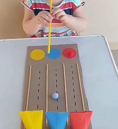 a young child is playing with some sort of game on the table and it looks like they are making something out of construction paper