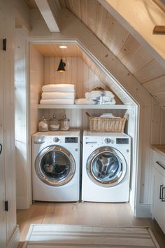 a washer and dryer in a small room under a slanted ceiling with shelves