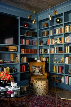 a living room filled with lots of books and furniture next to a wall mounted tv