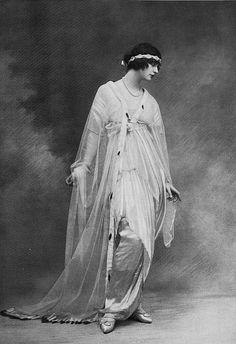 an old fashion photo of a woman wearing a veil and dress with her hands on her hips