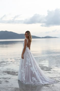 a woman standing in the water wearing a wedding dress