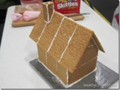 a house made out of graham crackers on top of a table next to other items