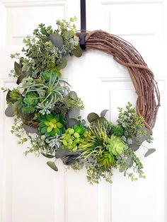 a wreath with succulents and greenery hangs on a door