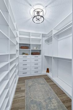 an empty walk - in closet with white shelves and drawers, carpeted flooring