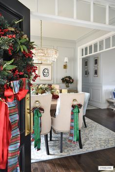 a dining room decorated for christmas with bows on the chairs