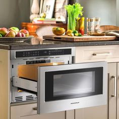 an oven with the door open in a kitchen next to some fruits and vegetables on a counter