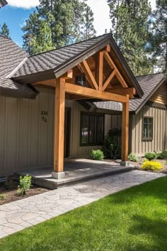 the front entrance to a home with an attached porch and covered patio area, surrounded by lush green grass