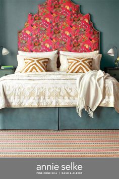 an ornate headboard in the middle of a bed with pillows and blankets on it