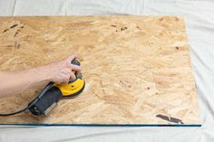 a person using a sanding machine on top of plywood planks that are being constructed