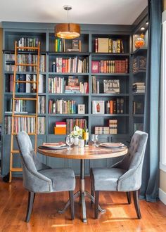 a dining room table surrounded by chairs and bookshelves