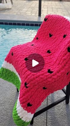 a watermelon blanket sitting on top of a chair next to a swimming pool