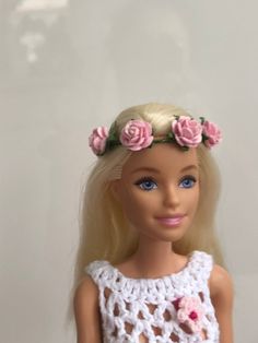 a doll with blonde hair wearing a crocheted dress and pink flowers in her hair