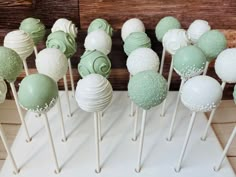 there are many green and white cake pops on the table with each one's own