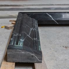 a black marble bench sitting on top of a wooden pallet next to another piece of wood