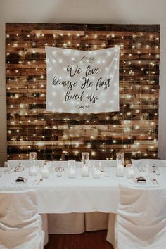 a white table topped with candles next to a wooden wall