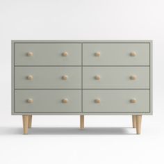 a grey dresser with wooden legs and knobs on it's drawers, against a white background