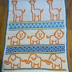 a crocheted afghan with elephants and giraffes in orange, blue, and white