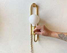 a person's hand is holding the handle on a wall light that has two balls attached to it