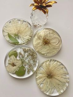 four glass plates with flowers on them and a vase in the middle one is empty