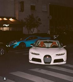 two cars parked in front of a building on the side of the road at night