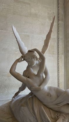 a statue of a woman sitting on top of a white marble slab holding a bird