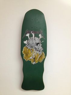 a green skateboard hanging on the wall with an image of two skulls and flowers