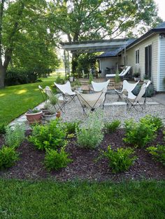 an outdoor patio with chairs and potted plants in the foreground, next to a house