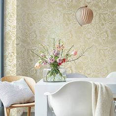 a vase filled with flowers sitting on top of a white table next to a chair