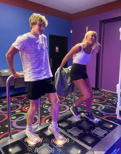 a man and woman are standing on a trampoline in a room with blue walls