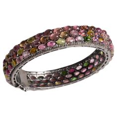 A lovely bangle bracelet with three rows of cabochon multi colored, oval tourmalines bordered with pave`set diamonds. Predominant tourmalines are the coveted pink. All set in an oxidized sterling silver. Inside circumference is 7". Tormalines total 55.80 carats, diamonds total 2.30 carats. The fine jewelry collection is sourced, designed or created by Deborah Lockhart Phillips. Through her international travels, she has cultivated prime resources for fine precious and semi-precious gemstones of unusual cuts in a variety of settings. Included in the collection are antique, high 22K gold pieces with intricate workmanship rarely found in the modern age. In creating the contemporary collection, Deborah works directly with artists and craftsmen to bring cutting edge jewelry designs directly to Modern Bangle, 18k Gold Bangle, Star Bangle, Diamond Bangle Bracelet, Modern Bracelets, Sterling Silver Bangle Bracelets, Diamond Bangles Bracelet, Diamond Bangle, Silver Bangle Bracelets