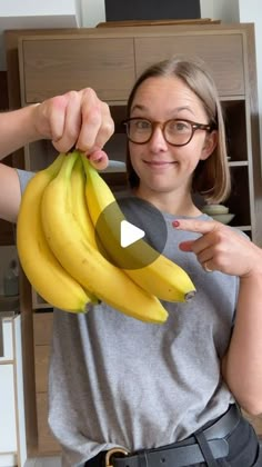 a woman holding up a bunch of bananas