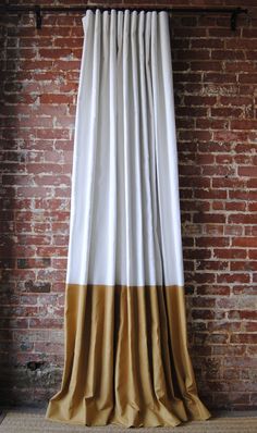 a brick wall with a white and gold curtain