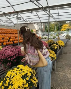 a woman is looking at flowers in a garden center with lots of orange and yellow flowers