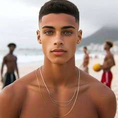 a young man standing on top of a sandy beach next to the ocean with people in the background