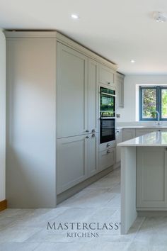 a large kitchen with an island in the middle of it and two windows above it