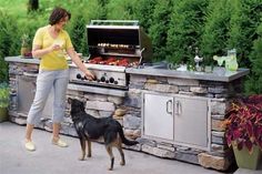 a woman standing next to a dog in front of an outdoor grill