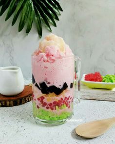 an ice cream sundae in a glass on a marble countertop next to a wooden spoon