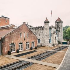 an old brick building with train tracks in front of it and a flag on the roof