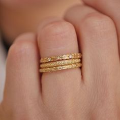 a woman's hand with three gold rings on it