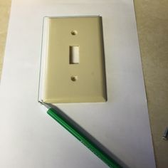 a white light switch plate sitting on top of a table next to a green pencil